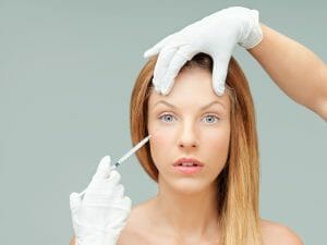 Young woman with doctor hands injecting botox
