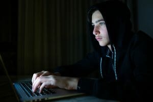 Young boy in a dark room with laptop. Hacker with a laptop.