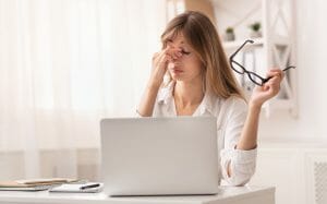 Frustrated businesswoman massaging nosebridge sitting at workplace