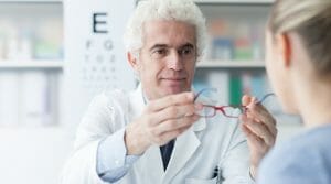 Optician giving glasses to the patient